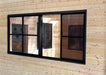 Interior of Sawmill Structures Eze Breeze Sunroom Cabin shows a black-framed sliding window on a smooth pine wall