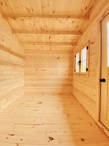 Interior of the Sawmill Structures Bluewater Den 67 Garden Room from the opposite angle, showing the door, windows, and smooth wooden flooring