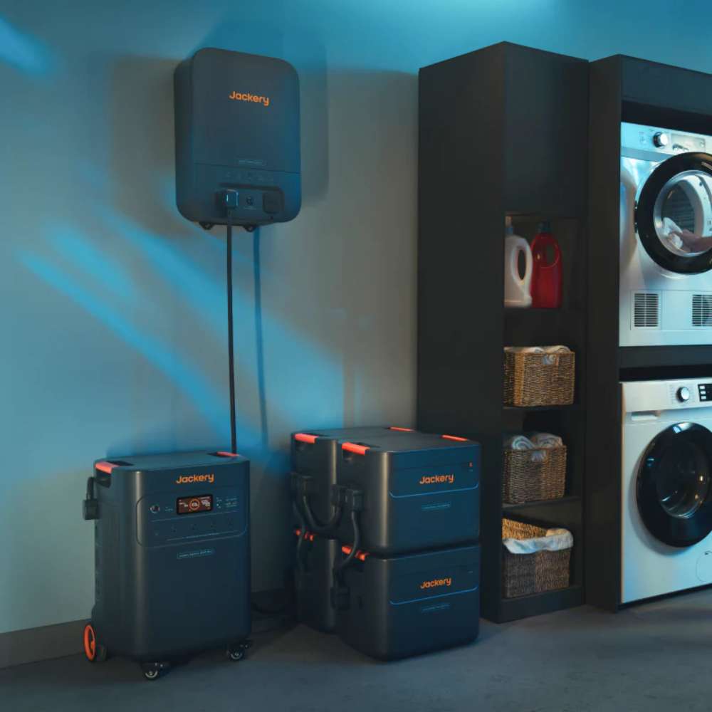 Jackery Battery Pack 5000 Plus installed with a home energy system in a laundry room beside a portable power station and stacked expansion batteries