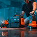 Jackery Explorer 2000 V2 Portable Power Station powers work lights and equipment in a workshop while a person prepares tools nearby