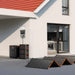 Jackery HomePower 3600 Plus Battery Pack stacked beside a Jackery power station and solar panels outside a house