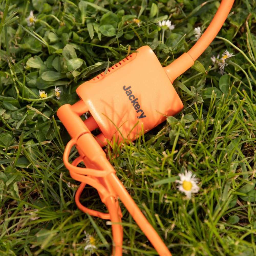 Jackery Solar Panel Connector resting on grass with attached orange charging cables