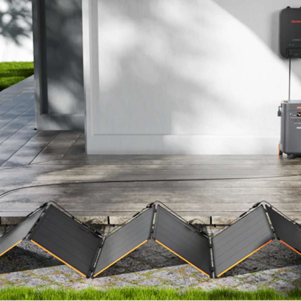 Jackery SolarSaga 500X Solar Panel is unfolded on the ground outside a home, connected to a backup power system for solar charging