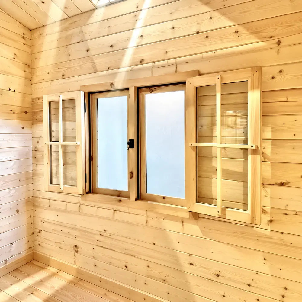 Double wooden windows with clear glass and protective outer shutters set into the sunlit pine wall of the Jumbo Grand Loft 130 SD.