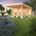 A twilight rendering of the GardenHouse24 USA Keno 70 Garden Room depicts a cozy, lit-up interior surrounded by a beautifully landscaped yard