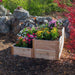 Landscaped yard scene featuring the Outdoor Living Today 3.5×4 Tiered Cedar Corner Raised Garden Bed in the middle