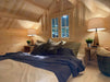 Loft bedroom of the Sawmill Structures Grand Loft 107 Deluxe DD Garden Room is softly lit with two bedside lamps, showcasing a double bed and wood-paneled slanted ceiling