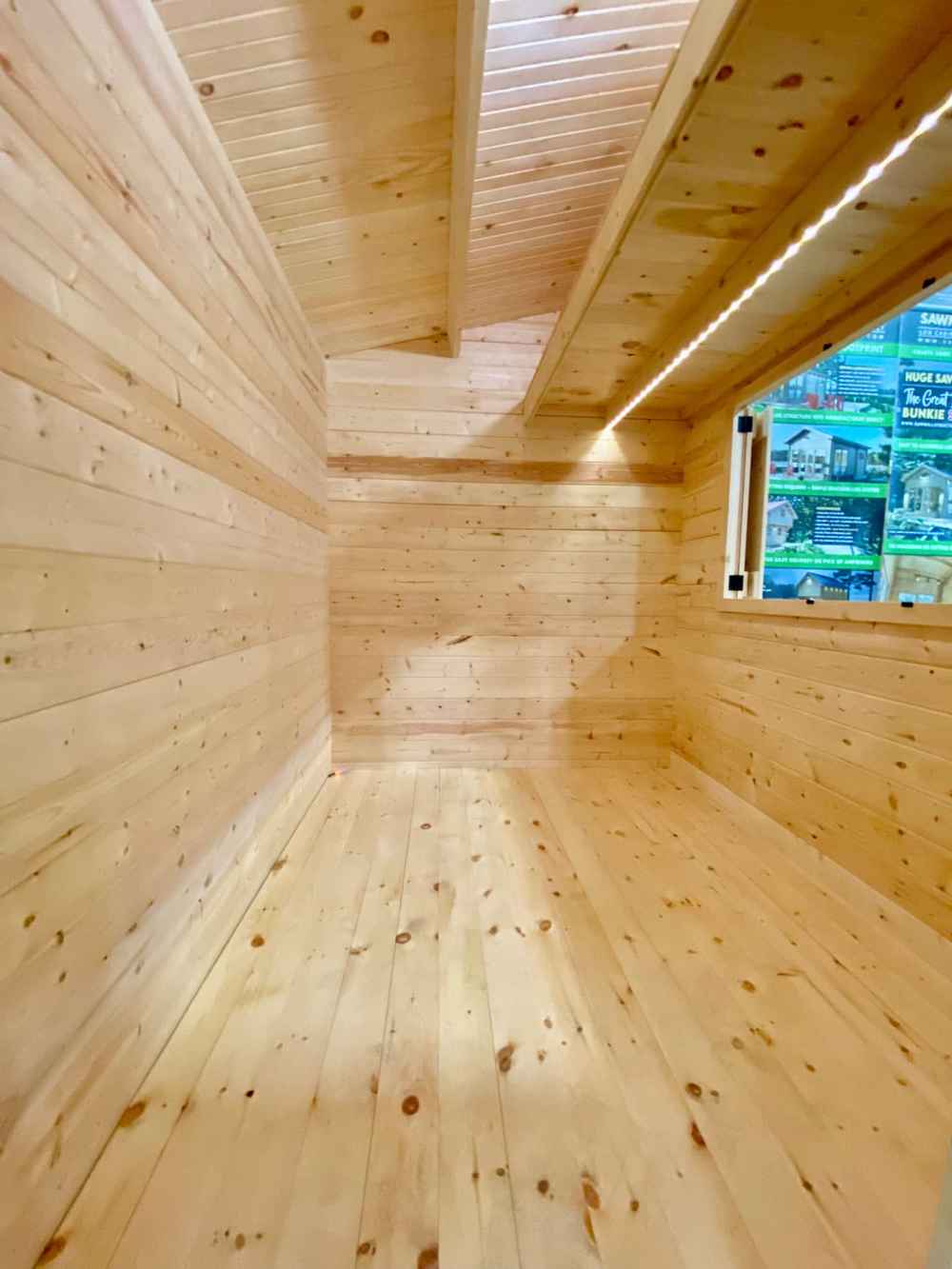 Long, narrow wooden interior of the Sawmill Structures The Lakeside Versa Cabana 67 Garden Room highlights its spacious floor and ceiling beams
