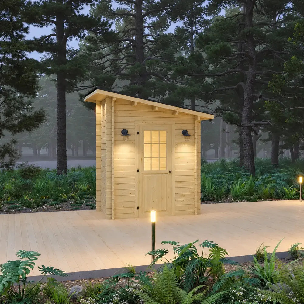 Straight front view of the Loo Loo House featuring a warm-lit glazed wooden door, matching black wall sconces, a sloped roof, and pathway lighting among forest greenery.