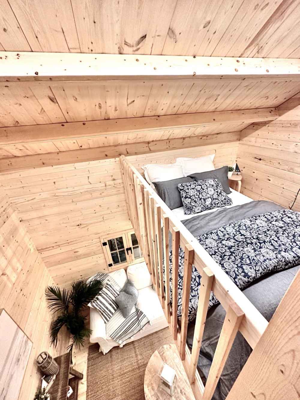 Looking down from the loft in the Sawmill Structures Ontario Grand Loft 107 SD Garden Room, you see the main living area with a couch, rug, and decor below