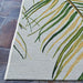 Lower left corner of Couristan Dolce Indoor/Outdoor Rug - Bamboo Forest/Frost rests on stone flooring with long green and yellow leaves woven