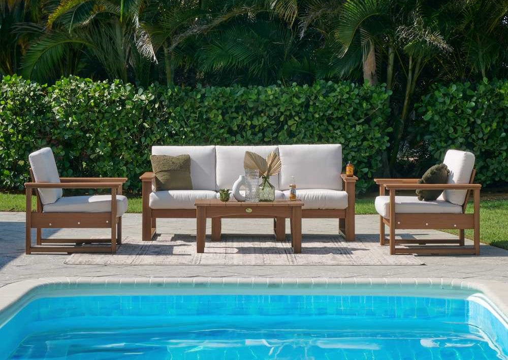 LuxCraft Arcadia Furniture Set includes a cushioned sofa, two matching armchairs, and a coffee table arranged beside a swimming pool
