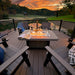 LuxCraft Hearthside Furniture Set is beautifully arranged on a scenic deck overlooking a tranquil lake at sunset, with a glowing fire pit at the center