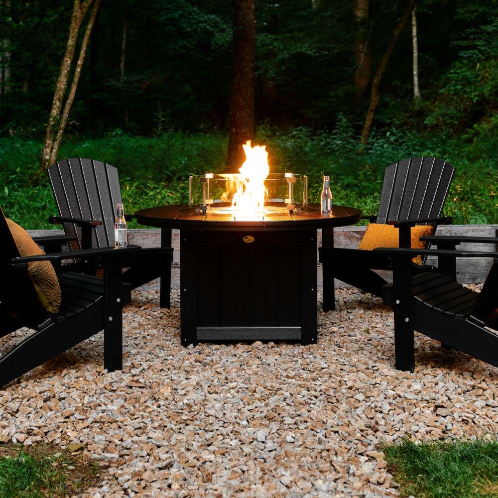 LuxCraft Lumin Fire Pit 46 Round Furniture Set showcases a glowing fire in a round table, encircled by black Adirondack chairs for a cozy outdoor setting