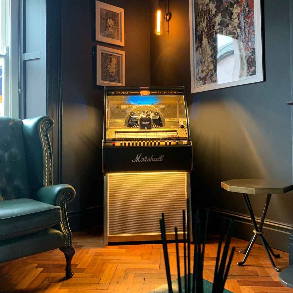 Marshall Rocket Vinyl Jukebox - Black is displayed in a cozy living room, radiating a warm glow from its illuminated panels