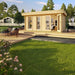 GardenHouse24 USA Miriam 44B Modern Garden Room is shown fully assembled in a lush outdoor setting with modern patio decor and art visible inside