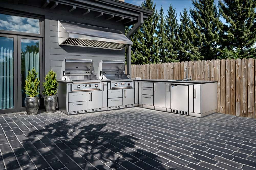 Modern patio setup with stainless steel grills and cabinets featuring the Sunstone Texas Tango 19ft Outdoor Kitchen Island Package