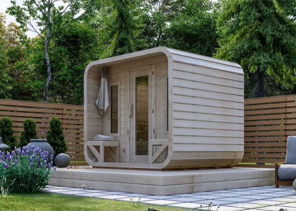 Modern wooden Sawmill Structures Box Sauna with curved edges and a glass door, set on a raised platform in a garden