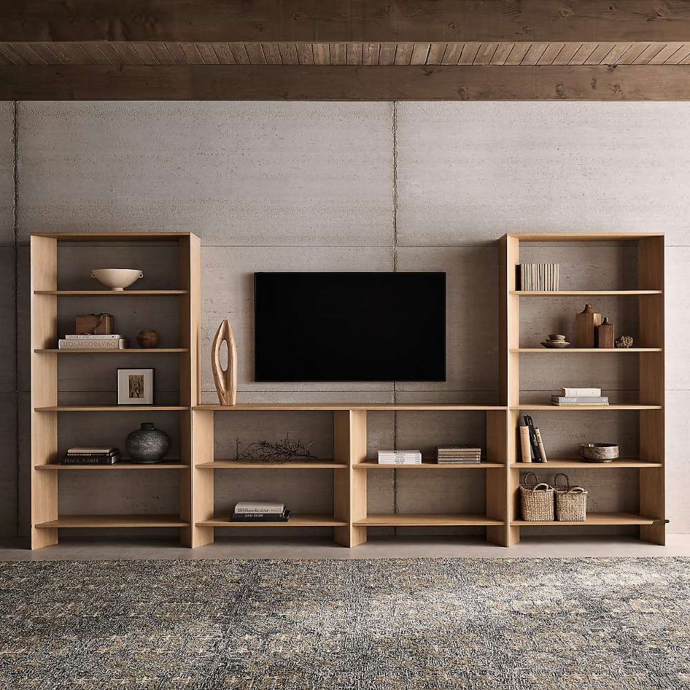 Modular living room wall uses Crate & Barrel Terrazza 38" Natural Solid Oak Wood 5-Shelf Storage Bookshelf on both sides of a mounted TV with open shelving