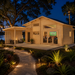 Montreal 70 glowing brightly at night as family and friends watch sports inside, surrounded by illuminated tropical landscaping beside a Central Florida lake.