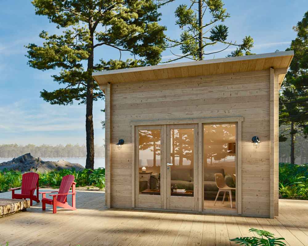 Morning light glows on the Sawmill Structures The Versa 107 70MM Garden Room, a small wooden cabin nestled by the lake with chairs placed