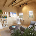 Cozy Multi Cube Versa 100 workspace with pine walls, a white desk and chair, laptop, bookshelves, television, sofa, and natural light.
