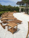 Multiple Westminster Teak Horizon Chaise Lounger chairs are arranged neatly around a spacious pool deck with palm trees and a house in the background