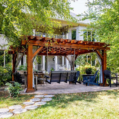 Nestled in a serene garden, the Brookside Timber Frame Highlan Oasis Pergola provides a shaded, stylish retreat with seating, string lights, and an elegant wooden design