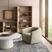 Next to a modern lounge chair and round coffee table, Crate & Barrel Terrazza 38" Natural Solid Oak Wood 5-Shelf Storage Bookshelf provides open display space for books and decor