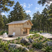 Front-angle view of the Northwood Grand DD cabin with glazed double doors, natural wood siding, a metal roof and white patio chairs.