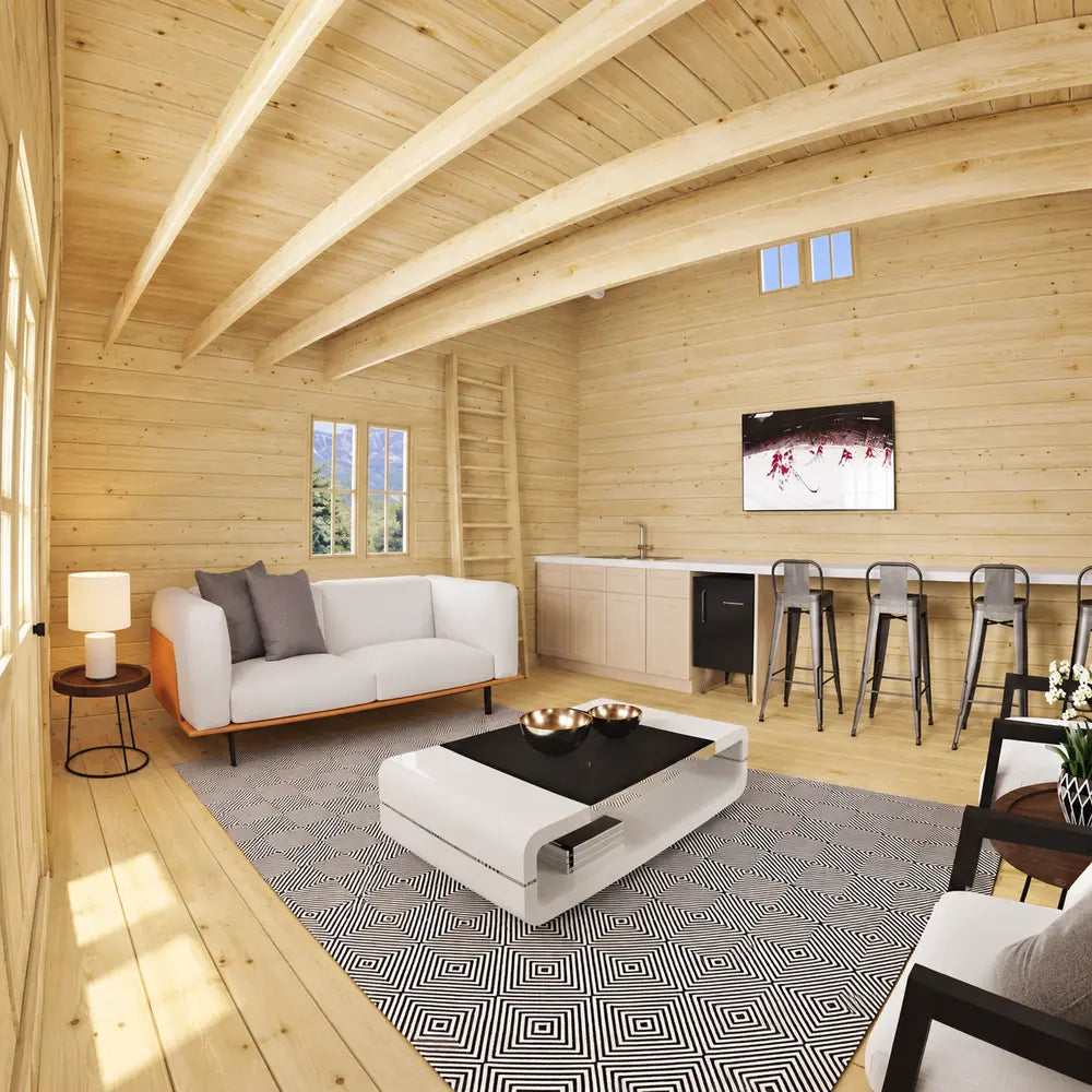 Northwood Grand living area with a white sofa, geometric rug, coffee table, kitchen counter and metal bar stools beneath exposed wooden beams.