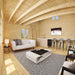 Northwood Grand living area with a white sofa, geometric rug, coffee table, kitchen counter and metal bar stools beneath exposed wooden beams.