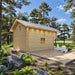 Rear view of the Northwood Grand cabin showing its natural wood paneling, small windows, metal roof and broad deck in a pine forest.