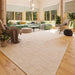 A cozy, sunlit living room with green and beige furnishings surrounded by large forest-view windows inside the GardenHouse24 USA Olivia 90 Garden Room