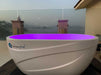 On an open balcony, a Dreampod Ice Bath with Chiller glows with purple lighting against a misty mountain and water view