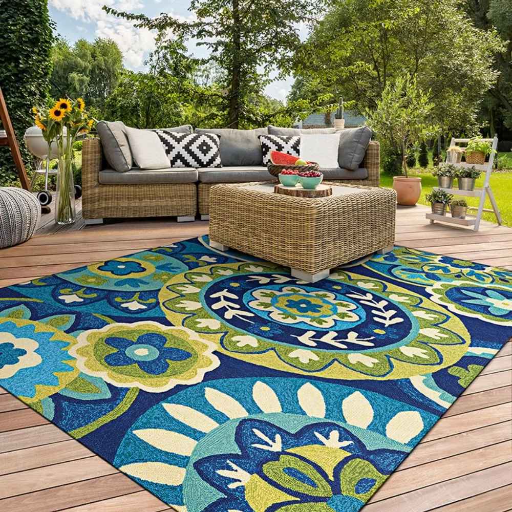 On a sunny patio, the Couristan Covington Indoor/Outdoor Rug - Rip Tide/Ocean-Green adds a vibrant pop of color beneath outdoor wicker furniture