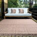 On a wooden patio, the Couristan Ascot Indoor/Outdoor Rug - Windowpane/Rose sits under a cushioned bench, adding cozy charm to the outdoor setting