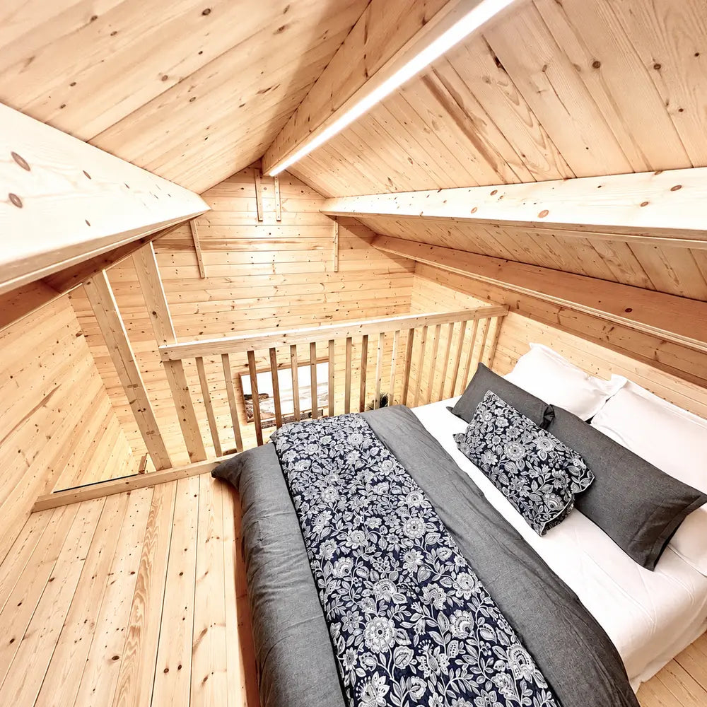 Bright Ontario Grand Loft 107 SD loft bedroom with a dark double bed, sloped wood ceiling, and railing overlooking the space below.