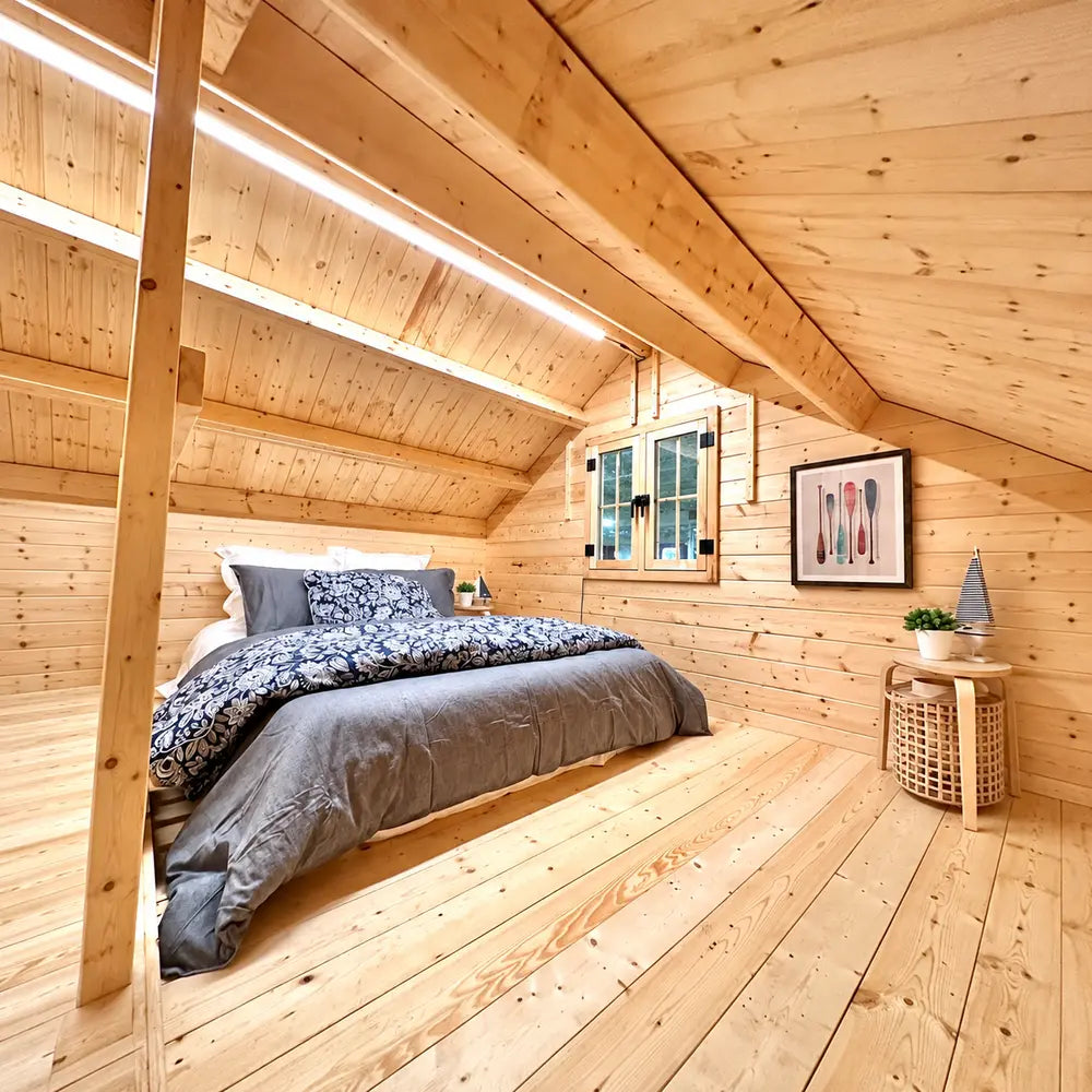 Ontario Grand Loft 107 SD loft bedroom with a dark double bed, natural pine walls, slanted ceiling, window, framed artwork, and bedside table.