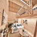 Double-height Ontario Grand Loft 107 SD living room with a white sofa below, wooden loft railing, loft bed, plants, and tall pine walls.