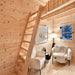 Simple wooden ladder leading to the Ontario Grand Loft 107 SD loft above a cozy sitting area with white chairs and warm lighting.