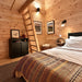 Ontario Grand Loft 107 SD main-floor bedroom with a dark bed, rustic ladder to the loft, framed artwork, and warm pine walls.