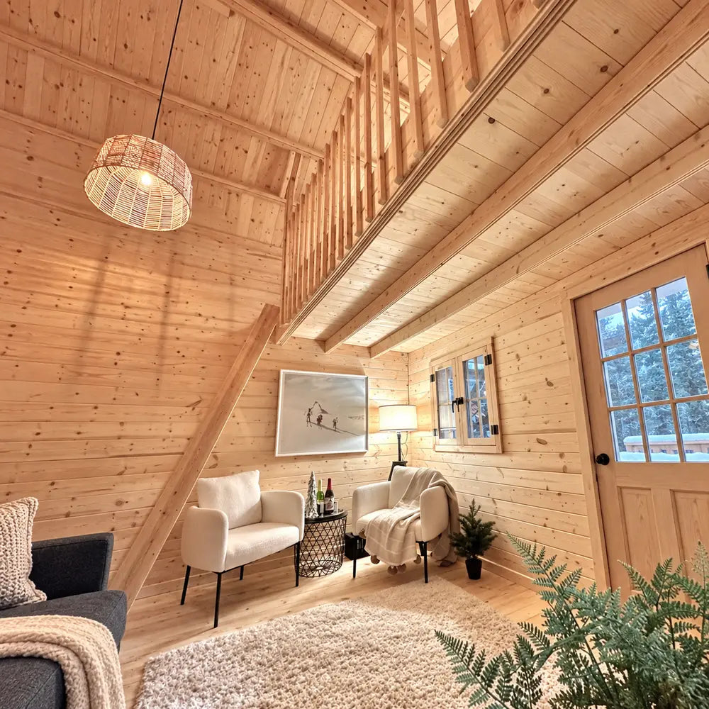 Bright sitting area beneath the Ontario Grand Loft 107 SD loft with two white chairs, a side table, lamp, tall window, and pale pine walls.