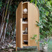 Open Crate & Barrel Annie 38" Natural Storage Cabinet displaying shelves with decorative bowls and books in an outdoor garden setting
