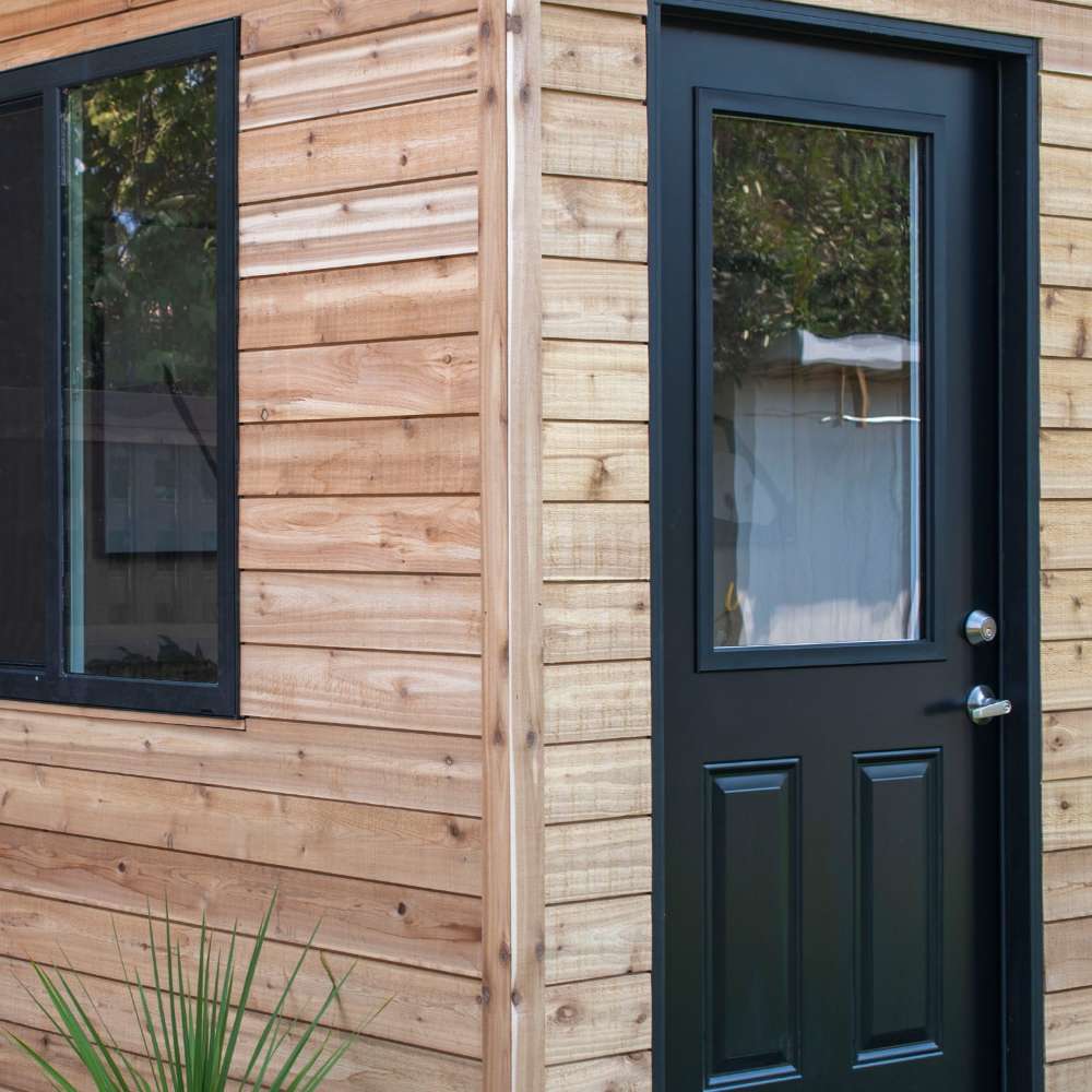 Outdoor Living Today 12×8 Saltbox Studio Outdoor Office is displayed in a close-up of the corner featuring the door, window, and clean cedar panel finish
