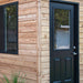 Outdoor Living Today 12×8 Saltbox Studio Outdoor Office is displayed in a close-up of the corner featuring the door, window, and clean cedar panel finish