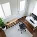 Outdoor Living Today 12×8 Saltbox Studio Outdoor Office is shown from above inside, featuring a desk setup, office chair, plants, and a small bookshelf on a rug