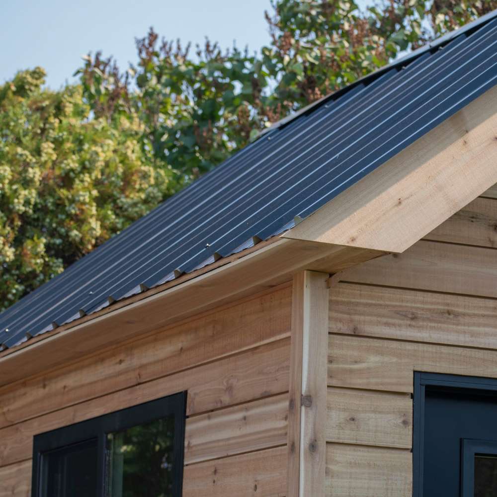 Outdoor Living Today 12×8 Saltbox Studio Outdoor Office is shown in a close-up focusing on the black metal roof and smooth cedar siding