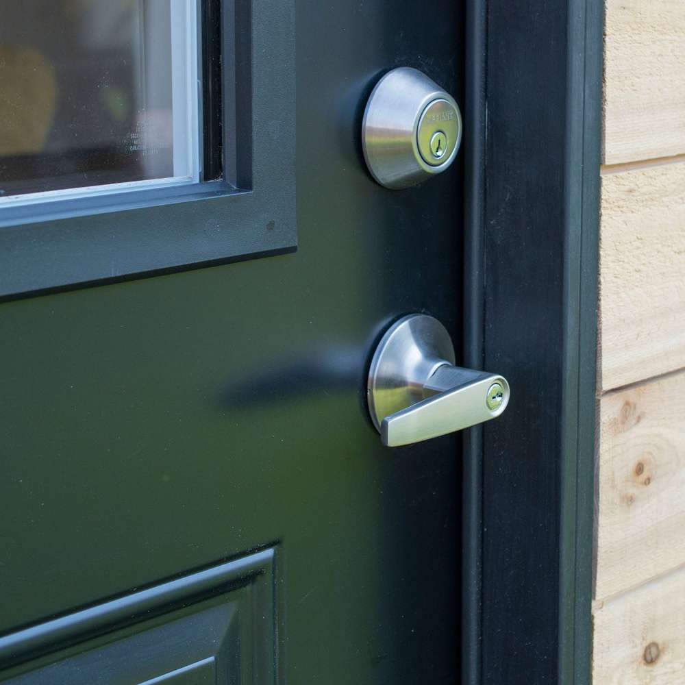 Outdoor Living Today 12×8 Saltbox Studio Outdoor Office is shown in a close-up of a black door featuring a silver handle and lock against cedar siding