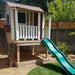 Outdoor Living Today 6x6 Little Cedar Playhouse & Sandbox includes white porch rails, side handles, and a long green slide in a backyard